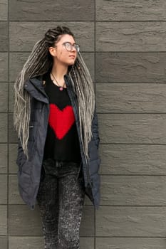 Cute young woman with dreadlocks hairstyle looks informal and unusual.