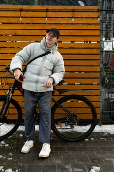 Bike rental concept. A man walks through the city in winter with a bicycle.