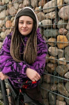 Lifestyle concept. Young woman with piercings and dreadlocks rides a bicycle.