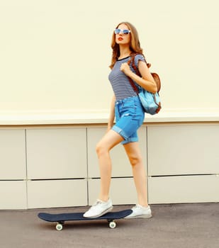 Portrait of stylish young woman with skateboard in the city