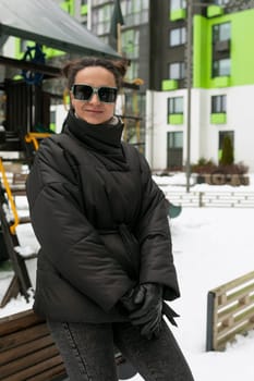 Young pretty woman in a winter jacket walking on the playground.