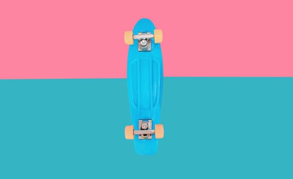 Close up of stylish blue skateboard on colorful pink background