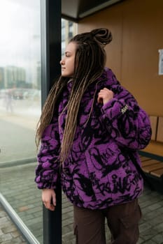 Street portrait of a young woman with piercings and African dreadlocks.
