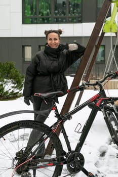 Lifestyle concept, young brunette woman walking down the street with a bike.