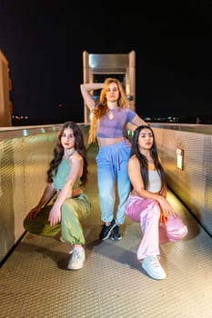Vertical portrait of a group of three beauty young breakdancers posing together at night in a bridge