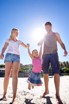 Holding hands, love and happy family at a beach with swing, support and care while bonding in nature. Freedom, travel and kid with parents at the ocean for morning games, fun or adventure at the sea.