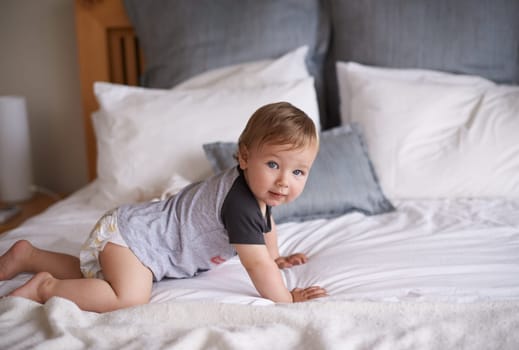 Boy, baby and crawl on bed in portrait, joy and kid for motor skills in bedroom on weekend. Child development, happy toddler and calm or comfortable, wellness and learn for health and positive growth.