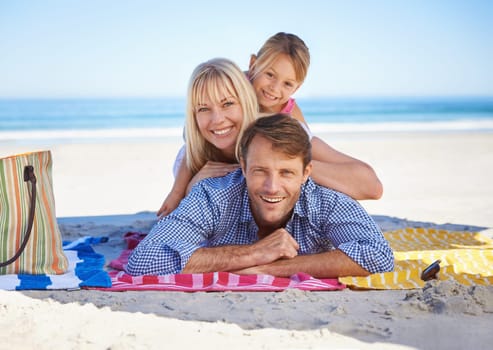 Parents, girl and portrait on blanket at beach with care, love and bonding in summer to relax on holiday. Father, mother and daughter with picnic, connection and happy by sea in sunshine on vacation.