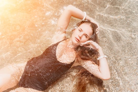 Woman travel sea. Young Happy woman in a long red dress posing on a beach near the sea on background of volcanic rocks, like in Iceland, sharing travel adventure journey