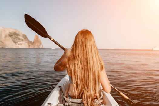 Woman in kayak back view. Happy young woman with long hair floating in transparent kayak on the crystal clear sea. Summer holiday vacation and cheerful female people relaxing having fun on the boat