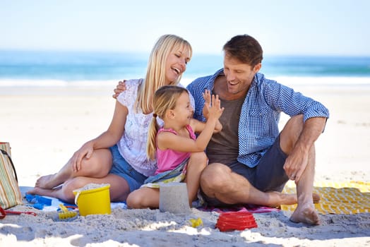 Family, beach and young girl on vacation, seaside and ocean with sand castle for bonding time. Holiday, overseas and summer season with parents, daughter and sunshine for happy memories in Hawaii.