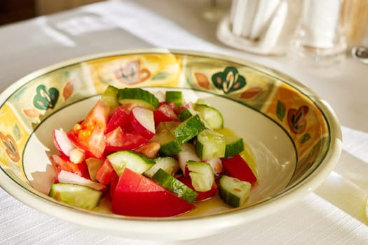 Simple tomato salad with cucumber sunshine. Salad bowl on white table Sunlight with harsh shadow