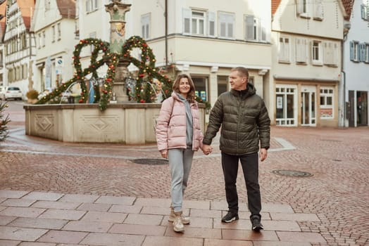 Loving couple of tourists walking around old town. Man woman couple walking europe old town Germany. Couple of lovers leisurely stroll in the cool autumn morning on the streets of a BIETIGHEIM-BISSINGEN (Germany). The guy holds his wife. Vacation, autumn, holiday. Couple Walking in Europe's Old Town