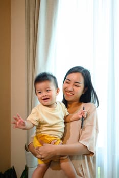 Happy young mother with her cute baby boy relaxing enjoy tender family moment at home.