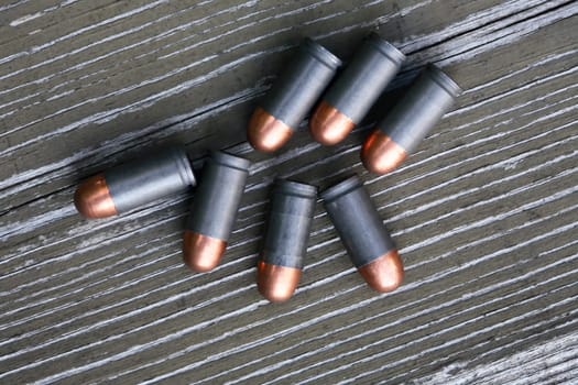 Closeup of few pistol cartridges on old wooden background