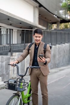 Asian businessman in a suit is riding a bicycle on the city streets for his morning commute to work. Eco transportation concept, sustainable lifestyle concept.