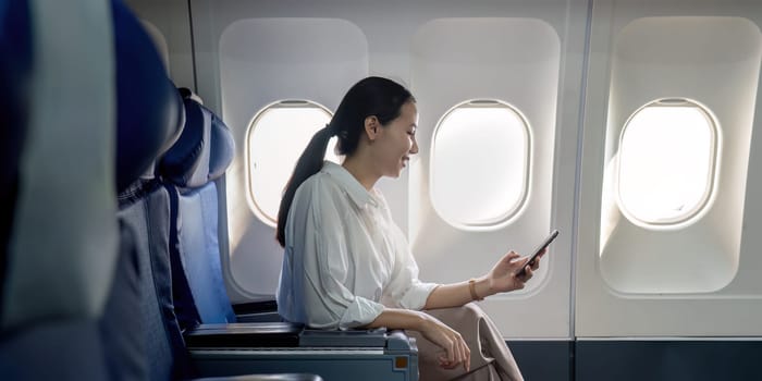 Successful young asian business woman sits in airplane cabin plane and working from anywhere. Flying at first class.