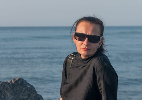 woman sitting on stones on the Mediterranean sea in winter at sunset 1