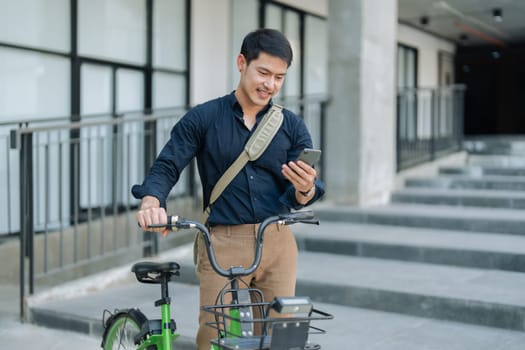 asian young businessman use smart phone while commuting in city. Eco friendly.