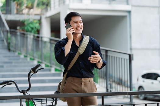 asian young businessman use smart phone while commuting in city. Eco friendly.