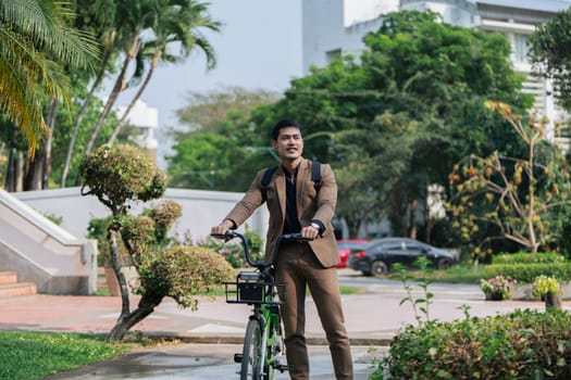 Young businessman in suit in city park bike to work eco friendly alternative vehicle green energy.