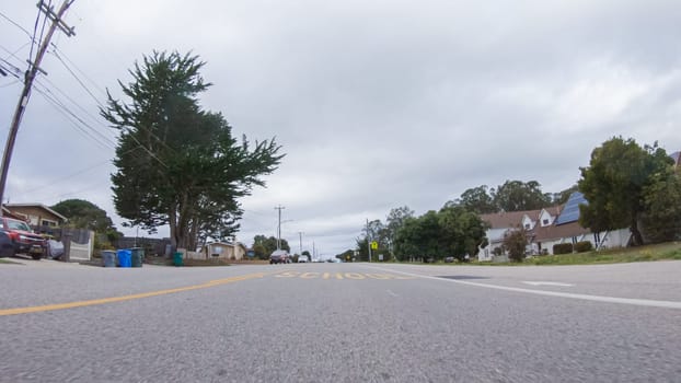 Santa Maria, California, USA-December 6, 2022-Vehicle navigates the streets of Morro Bay, California, during a cloudy winter day. The atmosphere is moody and serene as the overcast sky casts a soft light on the charming buildings and quiet streets of this coastal town.