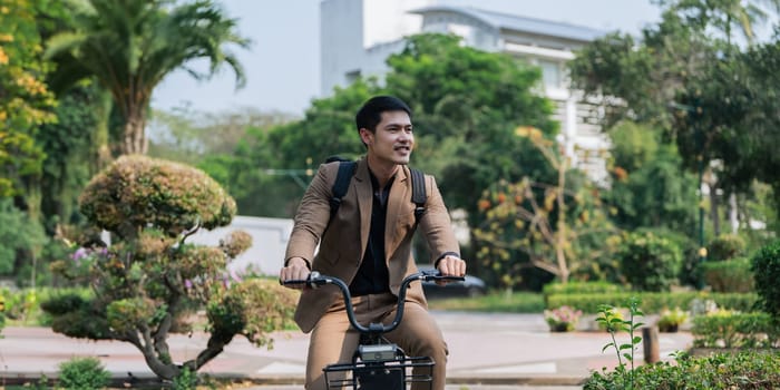 Young businessman in suit in city park bike to work eco friendly alternative vehicle green energy.