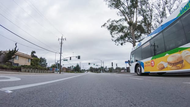 Santa Maria, California, USA-December 6, 2022-Vehicle navigates the streets of Morro Bay, California, during a cloudy winter day. The atmosphere is moody and serene as the overcast sky casts a soft light on the charming buildings and quiet streets of this coastal town.