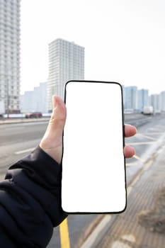 Phone with white screen in hand on city background close up