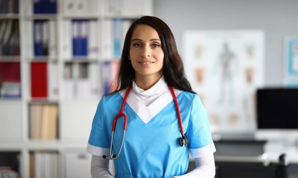 Portrait of good-looking young medical worker wearing uniform and red stethoscope. Professional nurse helping people in clinic. Modern medicine and hospital concept