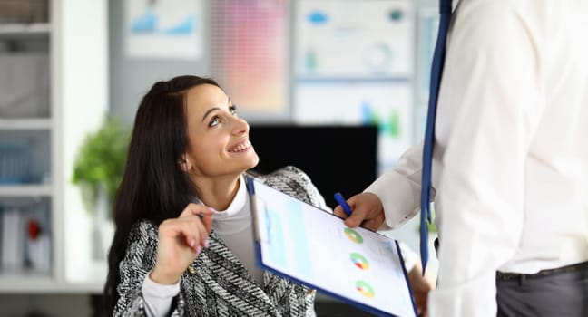 Portrait of smiling young woman get papers for sign. Happy lady in luxury costume. Clipboard with important documents. Business company and working moment concept