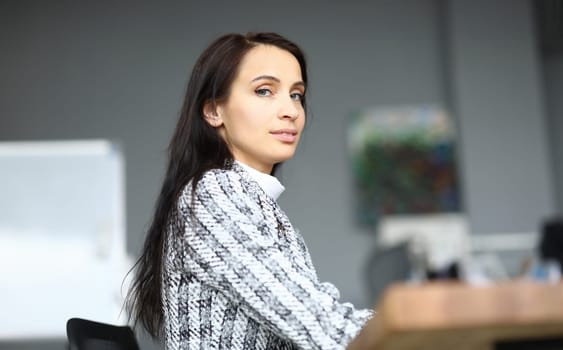 Close-up of beautiful young woman sitting in personal office. Luxury presentable suit on company worker. Copy space in right side. Business and secretary concept