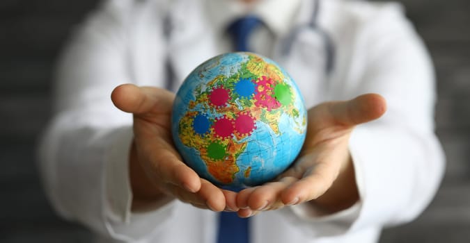 Close-up of person holding small globe in hands. Male in presentable suit. Extension of microbes and disease. Germs on world map. Infection and spread of virus concept