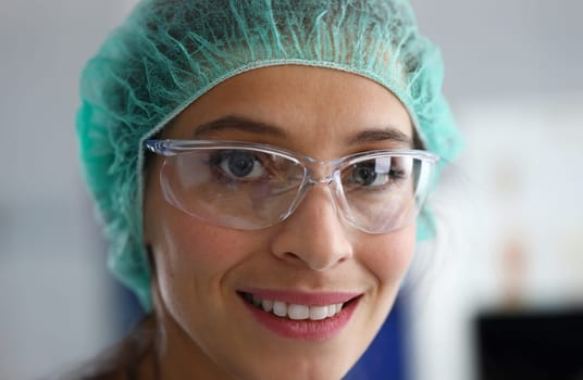 Close-up of beautiful scientist looking at camera with happiness and smile. Cheerful researcher in uniform working at laboratory. Science and experiment concept