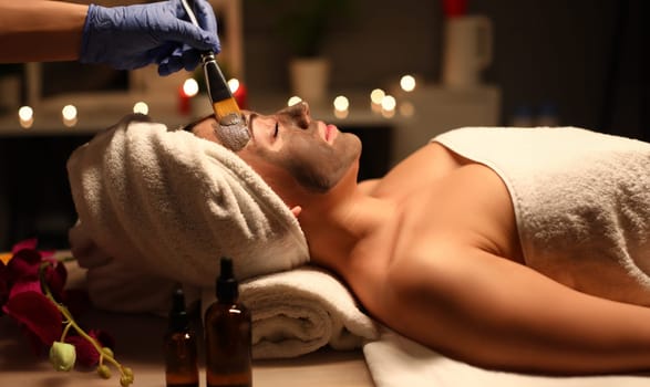 Close-up of sleepy woman applying skin cleansing face pack. Beautiful female person enjoying relax time in cosmetologist. Beauty and relaxation concept