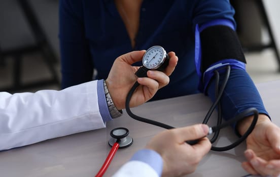 Close-up of doctor hands holding tonometer and measuring pressure to ill patient. Therapist making examination of elderly woman in clinic office. Health care and medicine concept