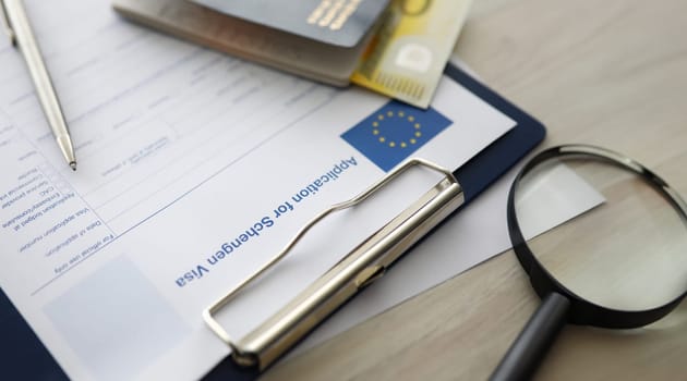 Close-up of silver pen and clipboard and application for shengen visa documents. Passport on table. Paper for applying to entry in European Union. Eu and travelling concept