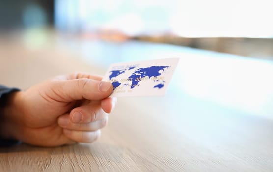 Close-up view of person hand holding white and blue plastic credit card. Online payment via internet or contactless terminal. Modern technology and progress concept