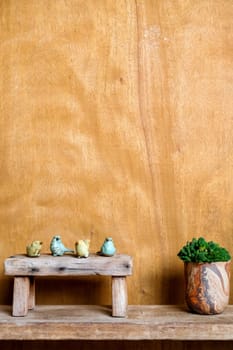 Still life image of Wooden bench and small birds with plant pot on wooden background.