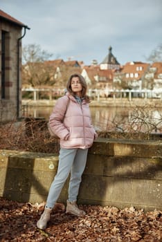 Young beautiful pretty tourist girl in warm hat and coat with backpack walking at cold autumn in Europe city enjoying her travel in Zurich Switzerland. Outdoor portrait of young tourist woman enjoying sightseeing