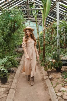 A beautiful young woman takes care of plants in a greenhouse. The concept of gardening and an eco-friendly lifestyle