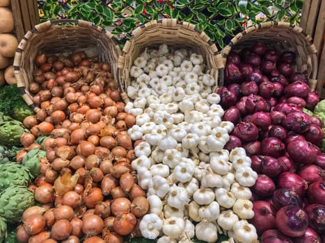 Garlic, white onions, red onions and artichokes sold in wicker baskets in supermarkets, High quality photo