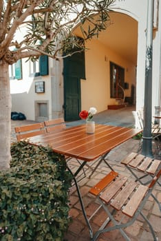 Empty cafe terrace with white table and chair. exterior of the cafe restaurant. interior Street cafe. Cozy street with flowers and French-style cafe table. Decor facade of coffeehouse with bike. Table on a summer terrace with cake and teapot. Garden table and chairs