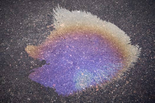 Color gasoline fuel spot on black asphalt, industrial pollution concept