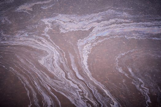 Marble spills on the water from stains of gasoline and oil. Abstract background from motor oil, gas or petrol spilled on asphalt.