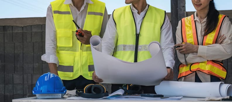 Civil engineer teams meeting working together wear worker helmets hardhat on construction site in modern city. Foreman industry project manager engineer teamwork. Asian industry professional team.