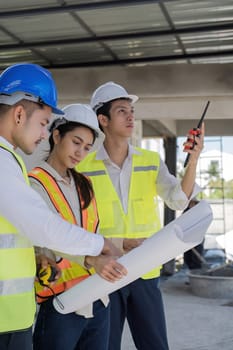 Civil engineer teams meeting working together wear worker helmets hardhat on construction site in modern city. Foreman industry project manager engineer teamwork. Asian industry professional team.