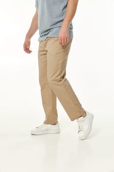 man wearing white sneakers and casual beige pants on studio background. side view