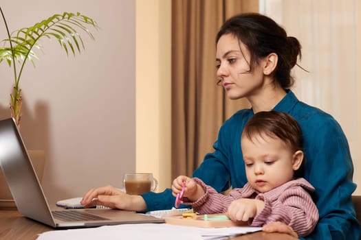 beautiful businesswoman working on laptop with her little child girl at home