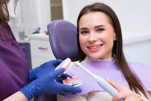 Woman patient learns correct technique for brushing teeth. Dental expert highlights importance of maintaining oral hygiene